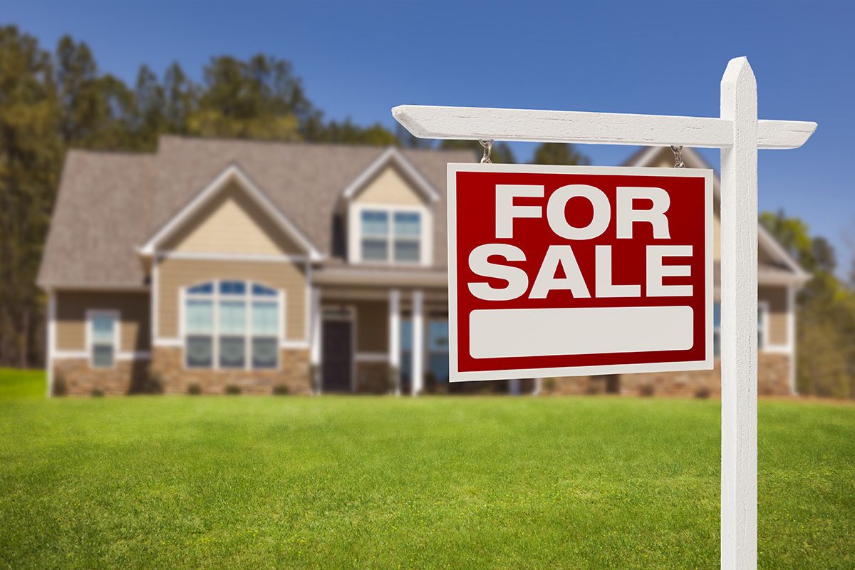 House with a for sale sign in the front yard